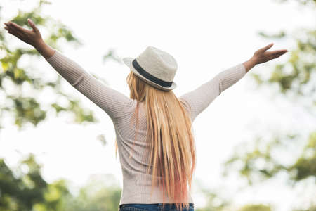 Young woman outdoor Raising hands enjoying nature. Woman lifestyle concept.