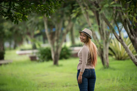 Attractive young woman enjoying her time outside in park with nature park background.の写真素材