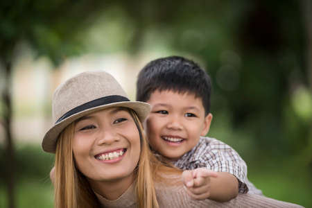 Happy young mother and son laughing little boy getting a piggyback ride on her back. Family concept.の写真素材