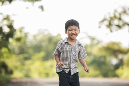 Portrait of little boy standing in the nature park smiling to camera.の写真素材