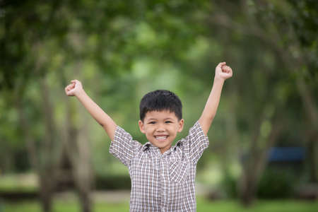 Little cute boy enjoying raising hands with nature over the blurred nature background.の写真素材