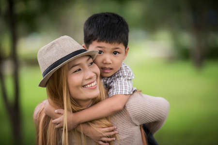 Happy young mother and son laughing little boy getting a piggyback ride on her back. Family concept.の写真素材