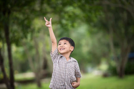 Little cute boy enjoying raising hands with nature over the blurred nature background.の写真素材