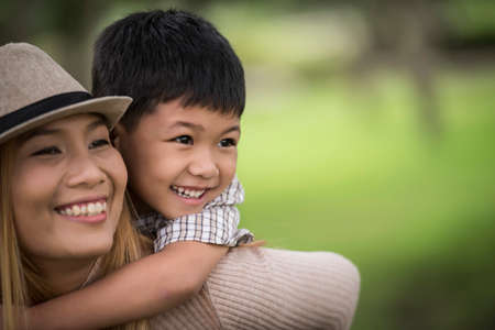 Happy young mother and son laughing little boy getting a piggyback ride on her back. Family concept.の写真素材