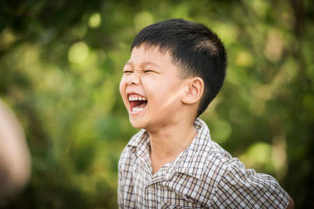 Portrait of happy little boy laughing while he play in the park.の写真素材
