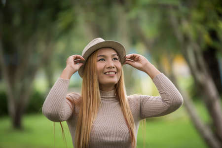 Attractive young woman enjoying her time outside in park with nature park background.の写真素材