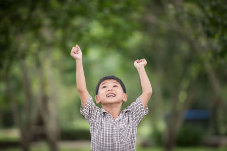 Little cute boy enjoying raising hands with nature over the blurred nature background.の写真素材