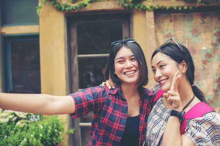 Image of two young happy women friends standing in urban city. Taking selfie together.の写真素材