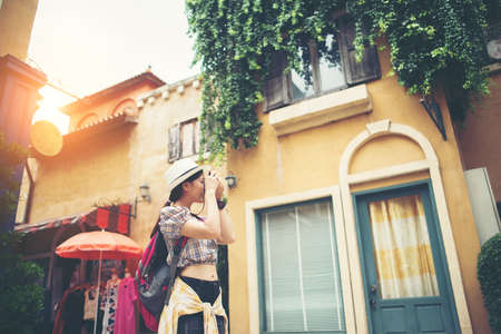 Portrait of young hipster woman backpack traveling taking photo in urban. Happy and enjoy with holiday.の写真素材