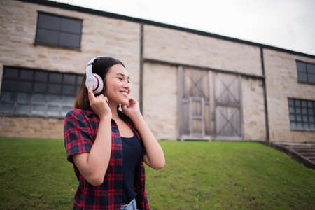 Close up of young hipster woman listening to music with mobile phone outdoor. Happy smiling girl listening to music with earphone.の写真素材