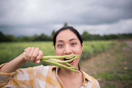 Close up off pretty farmer collect asparagus in hand and lokking at camera.の写真素材