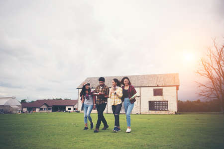 Group of student walking through the park after class. Enjoy talking together.の写真素材