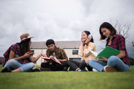 Group of student sitting at park after class. Enjoy talking together.の写真素材