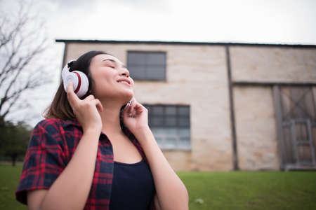 Close up of young hipster woman listening to music with mobile phone outdoor. Happy smiling girl listening to music with earphone.の写真素材