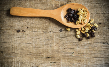 Coffee beans in a spoon on a wooden floor.の写真素材