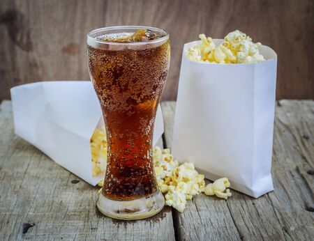 Cola with Ice and Popcorn on a wooden backgroundの写真素材
