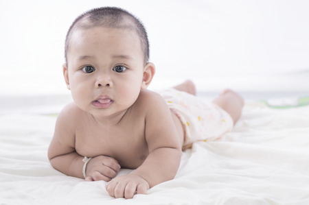 Portrait of a eight months old baby boy on the bed.の写真素材