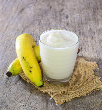 Banana smoothies with milk on wooden background.の写真素材