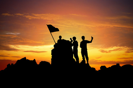 Silhouette of a champion on mountain peak at sunset.の写真素材