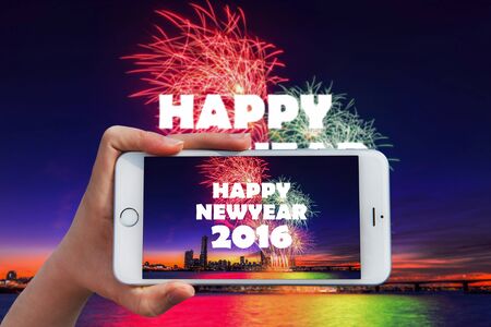Hand holding smart phone take a photo at happy new year 2016 and Firework dishplay.