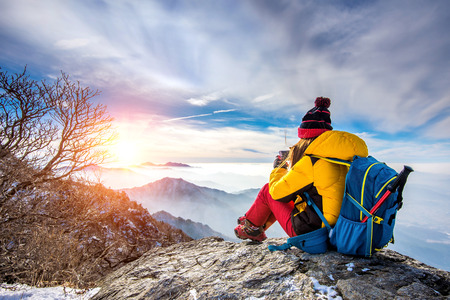 Young woman hiker taking photo with smartphone on mountains peak in winter.の写真素材
