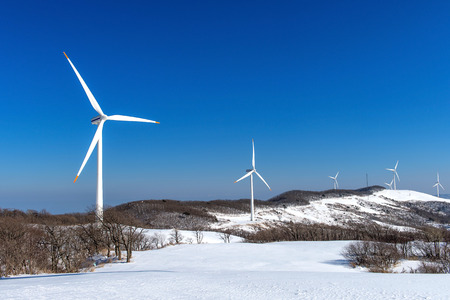 Wind turbine and blue sky in winter landscape.