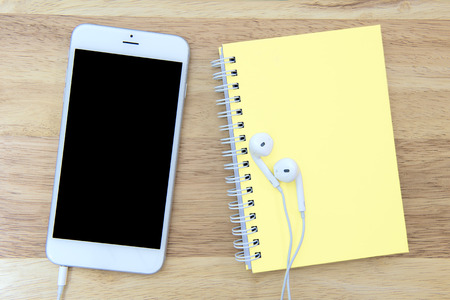 Phone and notebook with blank screen on wooden background.の写真素材