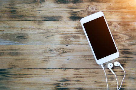Smartphone and headphones on wooden background. Retro toneの写真素材