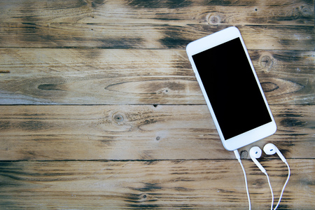 Smartphone and headphones on wooden background. Retro toneの写真素材