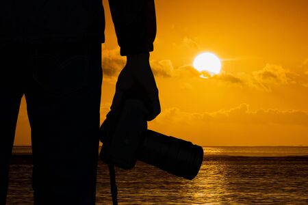 Silhouette photographer with camera and sunset blackground.の写真素材