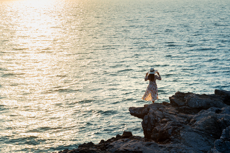 Young woman standing on the top of rock and looking at the seashore and sunset in Si chang island.の写真素材