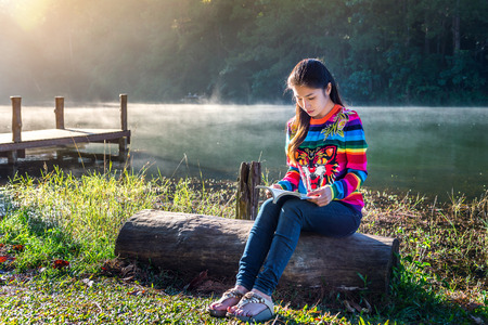 Young girl reading a book in the park.の写真素材