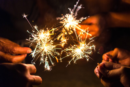 Hands of people holding sparkler, Bright festive Christmas sparkler.の写真素材