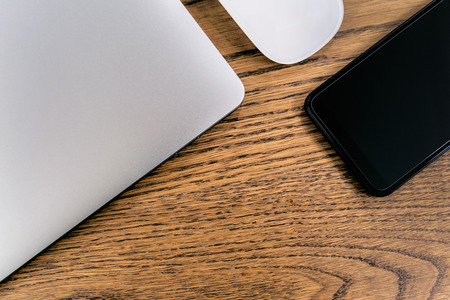 Laptop computer and smartphone, mouse on table. Office concept.
