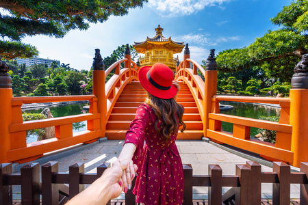 Women tourists holding man's hand and leading him to Golden Pavilion in Nan Lian Garden near Chi Lin Nunnery temple, Hong Kong.の写真素材