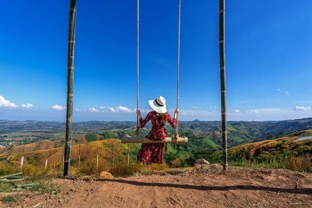 Young woman sitting on a swing and looking to nature.の写真素材