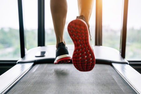 Male feet in sneakers running on the treadmill at the gym. Exercise concept.の写真素材