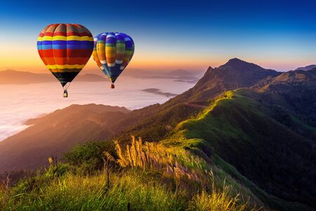 Landscape of morning fog and mountains with hot air balloons at sunrise.の写真素材