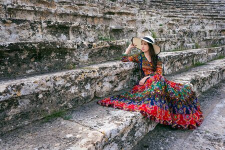 Woman in bohemian dress sitting on theater of Hierapolis ancient city in Pamukkale, Turkey.の写真素材