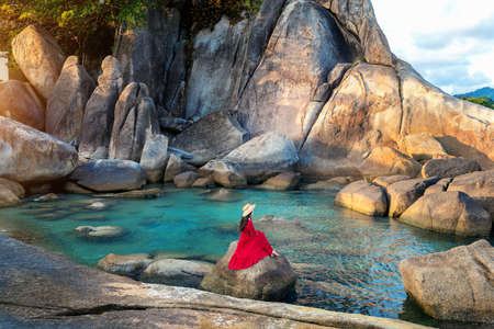 Tourist sitting on the rock near Grandfather and grandfather rock (Hin Ta and Hin Yai Rocks) on the Lamai Beach, Koh Samui, Thailand.の写真素材