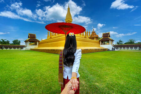 Women tourists holding man's hand and leading him to Phra that luang in Vientiane, Laos.の写真素材