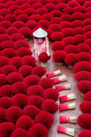 Asian woman wearing ao dai dress with Incense sticks drying outdoor in Hanoi, Vietnam.の写真素材