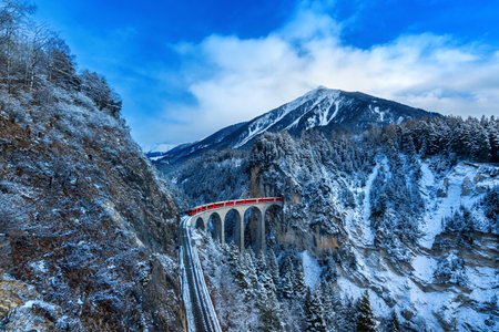 Landscape of Train passing through famous mountain in Filisur, Switzerland. Landwasser Viaduct world heritage with train express in Swiss Alps snow winter scenery.の写真素材