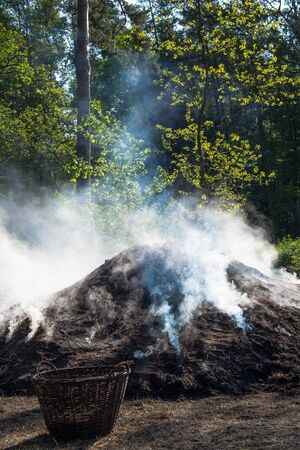 The constant treatment of the pile fire protects the success of the charcoal production.の写真素材