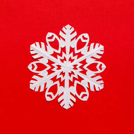 White paper snowflake on a red background, handmade new year decorationの写真素材