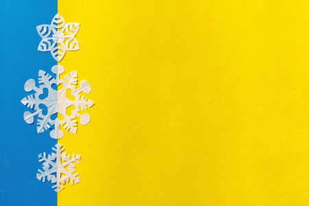White snowflakes cut out from tracing paper on the yellow and blue background, flat lay, copy spaceの写真素材