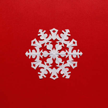White paper snowflake on a red background, handmade new year decorationの写真素材