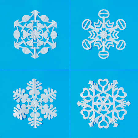 Set of white snowflakes cut out from tracing paper on a blue backgroundの写真素材