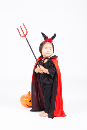 devil girl in black suit and red cape  with halloween pumpkin and tridentの写真素材