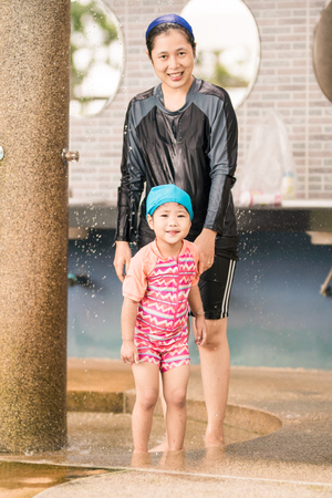 kid take a bath at swimming pool with motherの写真素材
